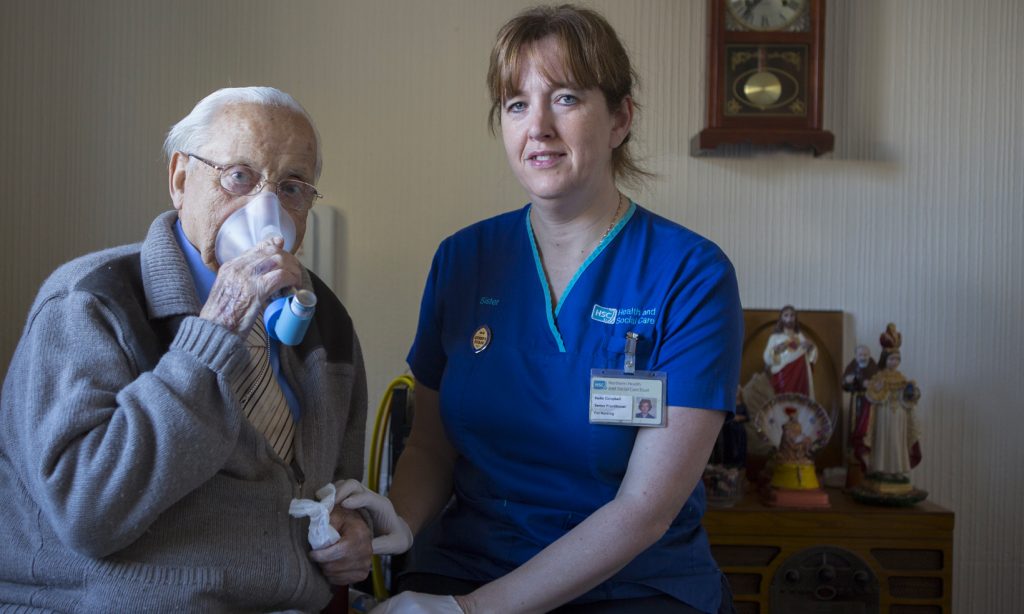 A district nurse helps a patient with breathing difficulties