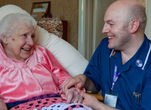 Male district nurse cheers up an elderly lady