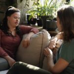 Two women sitting on a couch chatting